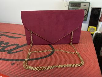 This is a burgundy faux suede envelope clutch bag with a gold-tone chain strap. 