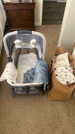 Baby bassinet with blankets and bag full of clothes