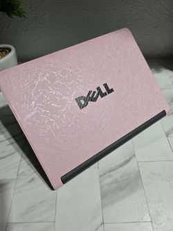 Pink Dell Chromebook has a textured pink skin on the outer lid. The device is black with a standard QWERTY keyboard and integrated touchpad. Great bat