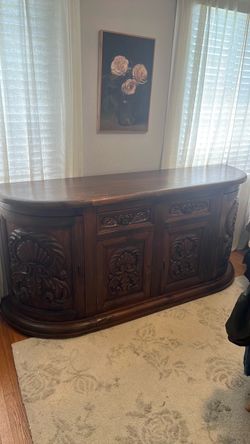 dark wood hand carved buffet  sideboard with curved ends and intricate  floral medallion  panels on the doors