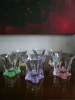 Set of six colored crystal whiskey glasses with geometric faceted design.