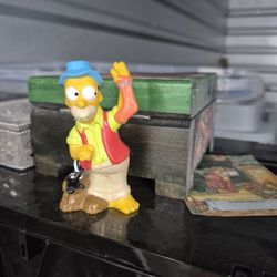 Homer Simpson Camping Figurine From One Of The First Episodes Ever. As Well As Coozey Dipicting The Same Episode