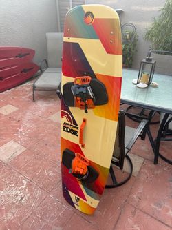 Liquid Force Edge twin-tip kiteboard (size 146 cm), featuring a multi-colored rainbow/strip design, orange foot straps/bindings, and an orange center