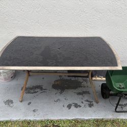 outdoor dining table with a glass top and metal frame.