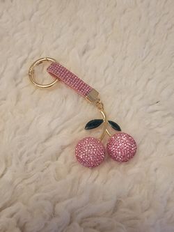 Cute cherry keychain features sparkling pink rhinestones and shiny dark green leaves on the stem