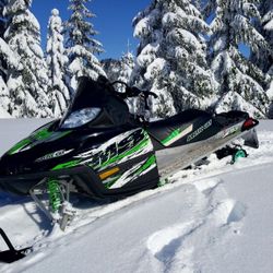 Two Running Snowmobiles And A Trailer 