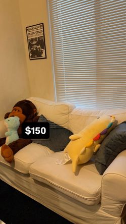 white ikea couch and two blue pillows