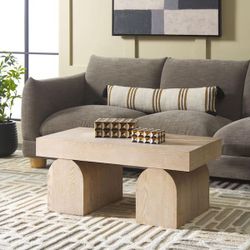 Safavieh Okashu coffee table, a modern-style piece made of wood and ash veneer, featuring geometric arched legs and a bleached white or light wood fin