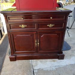 Hardwood unit in good condition. It features two drawers that slide very smoothly and two hinged doors at the top; the tabletop also extends. Please s