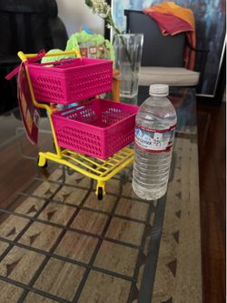 New Our Generation doll shopping cart. It is pink and yellow with two baskets. This accessory fits most 18in/46cm dolls.