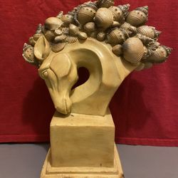 A horse head statue with a seashell mane, a decorative home accent piece.