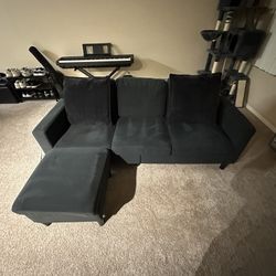 Dark grey L Shape Couch With ottoman And Dark grey Pillows.