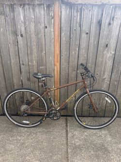 This is a brown Novato Buzz hybrid commuter bike.