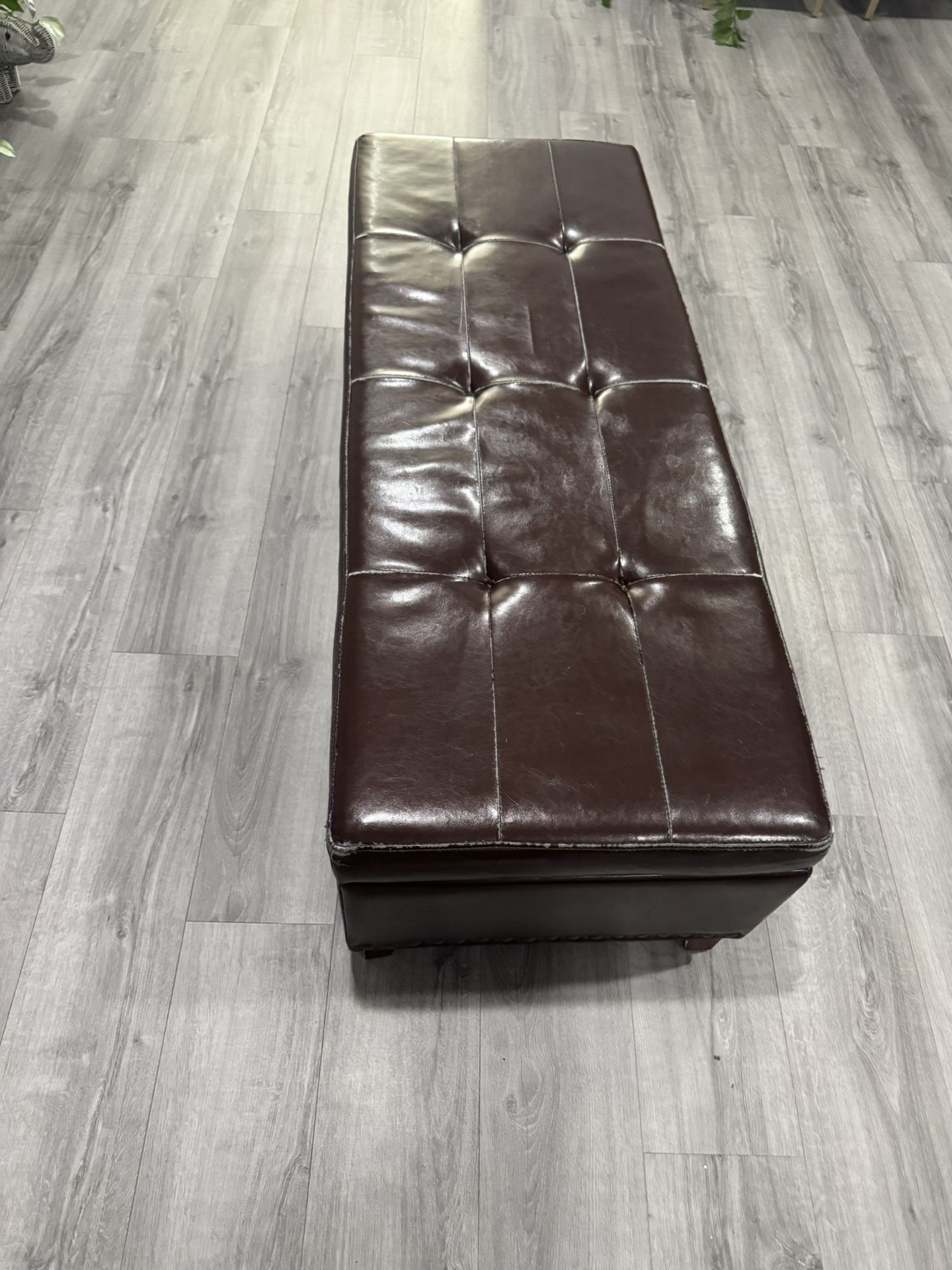 Tufted brown leather ottoman in good condition.