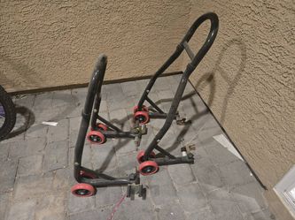 set of heavy-duty black steel motorcycle paddock stands (a front and rear wheel lift combo) featuring dual red wheels on each base and adjustable fork