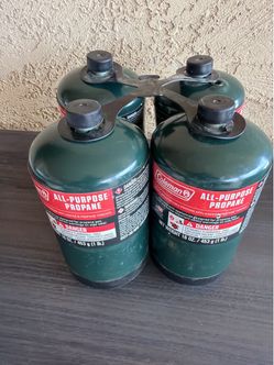Four Coleman all-purpose propane canisters, 16 oz (1 lb) each. Unused, caps on.