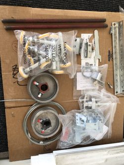 Garage door tune up kit, fastening rods, reels with cables, wheels, door lock, and emergency door latch opener.