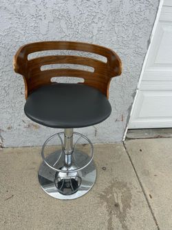Adjustable height bar stool with a sleek wooden backrest and chrome base.