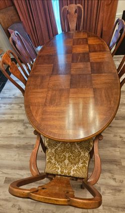 Elegant wood dining set with an oval table and six matching chairs. The tabletop has a decorative checkerboard wood veneer pattern and includes a prot