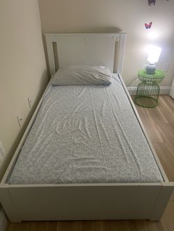 white IKEA twin beds with mattresses and built-in storage drawers underneath.