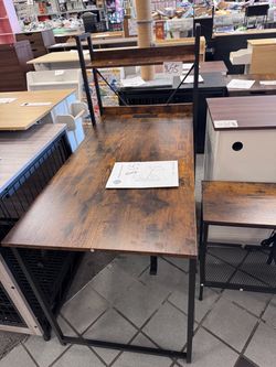 is rustic brown and black industrial computer desk features an integrated power outlet and an X-frame metal design.