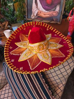 Traditional red velvet charro or mariachi hat with gold embroidery.