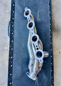 The image shows a polished stainless steel turbo exhaust header