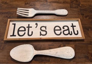 Big  wooden fork and spoon with let’s eat wooden sign