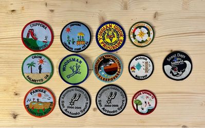 Collection of 12 embroidered merit & event patches, primarily from Texas-based scouting, camping, & adventure programs like Indian Guides, YMCA Advent