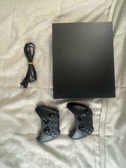 Black Microsoft Xbox One X 1TB Home Console. 2 controllers, console, power cord.