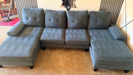 I'm selling a dark gray U-shaped sofa. It's used but in good condition with some signs of wear.