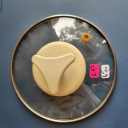 Clear Glass Lid With A White Plastic Handle For A Cookpot