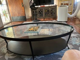 Table with a glass top perfect condition it’s black brown iron. It has four legs that it sits on. It’s very heavy this table.
