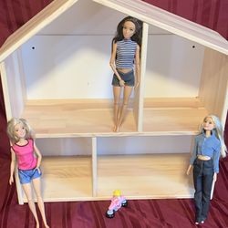 Toy wooden house and 3 Barbie dolls