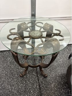 This BEAUTIFUL  item is a contemporary bronze wrought iron accent table featuring an ornate, openwork scroll-motif frame and a round tempered glass to
