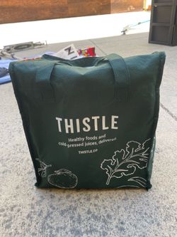 Thistle branded green insulated tote bag used for delivering healthy food and cold-pressed juices.