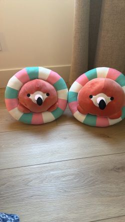 A set of two baby flamingo plushies, riding in a inner tubes