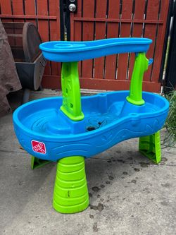 Fun blue and green water table for kids. It features a water slide and multiple levels for play. Great for outdoor fun on a warm day!