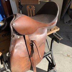 Leather English riding saddle with girth strap and stirrups good condition.