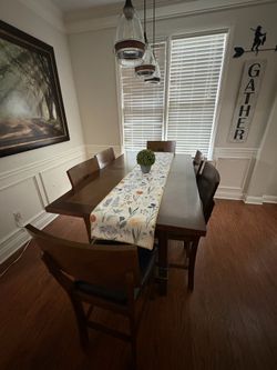 Counter-height wooden dining table with six wooden chairs