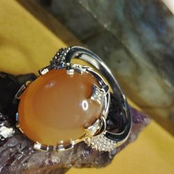PEACH MOONSTONE, A LARGE CABOCHON  LAYERED ON CLUSTERS OF ZIRCON.  STERLING- SETTING.  SIZE 6