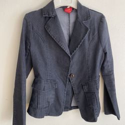 A slim-fit women's blazer in a deep grey (or charcoal black) color. • Fabric texture: The surface has distinct fine vertical stripes, resembling cordu