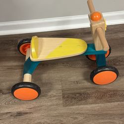 This is the B. toys Smooth Rider Wooden Trike, a ride-on toy for toddlers.