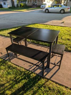 Black wood and metal dining set with bench seating and seats at the ends.
