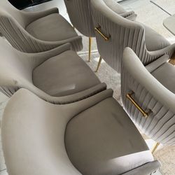 6 grey dining chairs with gold legs.