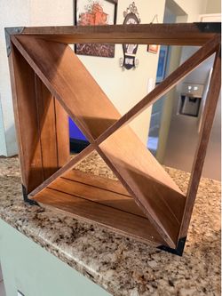 This is a small, freestanding wooden wine rack designed for a countertop or table