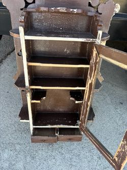 Rustic wooden wall cabinet is brown with a distressed finish. It has a single glass-front door that opens to reveal three internal shelves. Two small