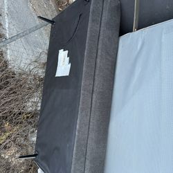 Gray cushioned sofa base or futon sleeper with attached legs.