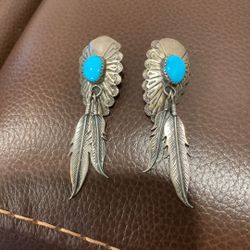 This is a pair of sterling silver and turquoise Native American Navajo feather dangle earrings