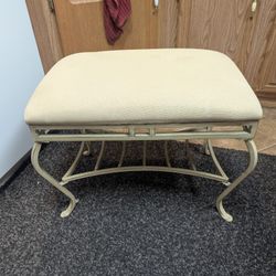 vintage Hollywood Regency style metal vanity bench with a light-colored upholstered cushion